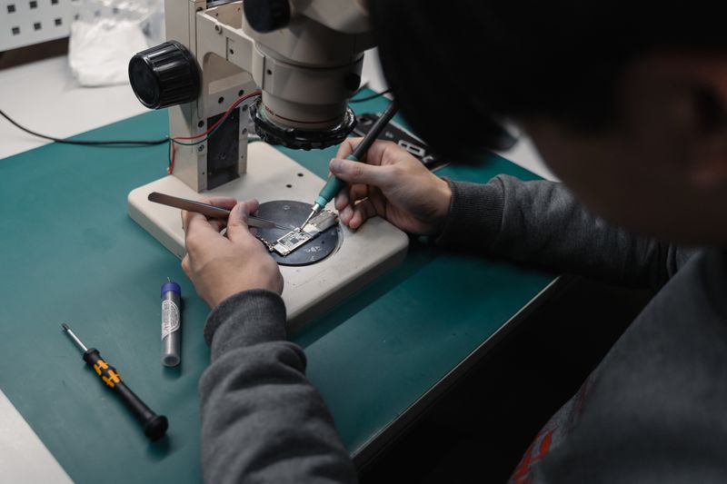 Serwisant naprawiający płytkę elektroniczną pod mikroskopem